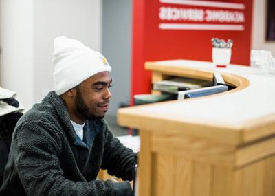 UHart student working at the Academic Services desk.